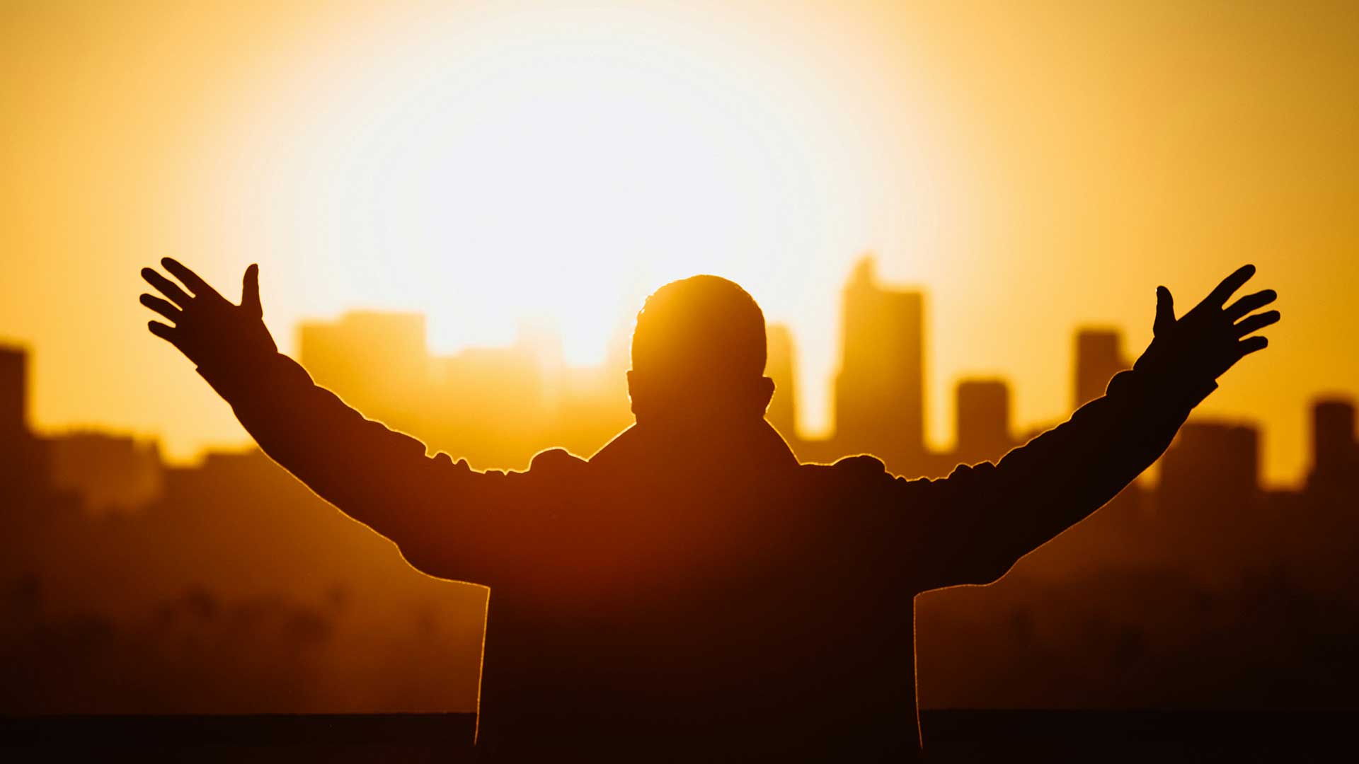 Silhouette with raised arms at city sunset