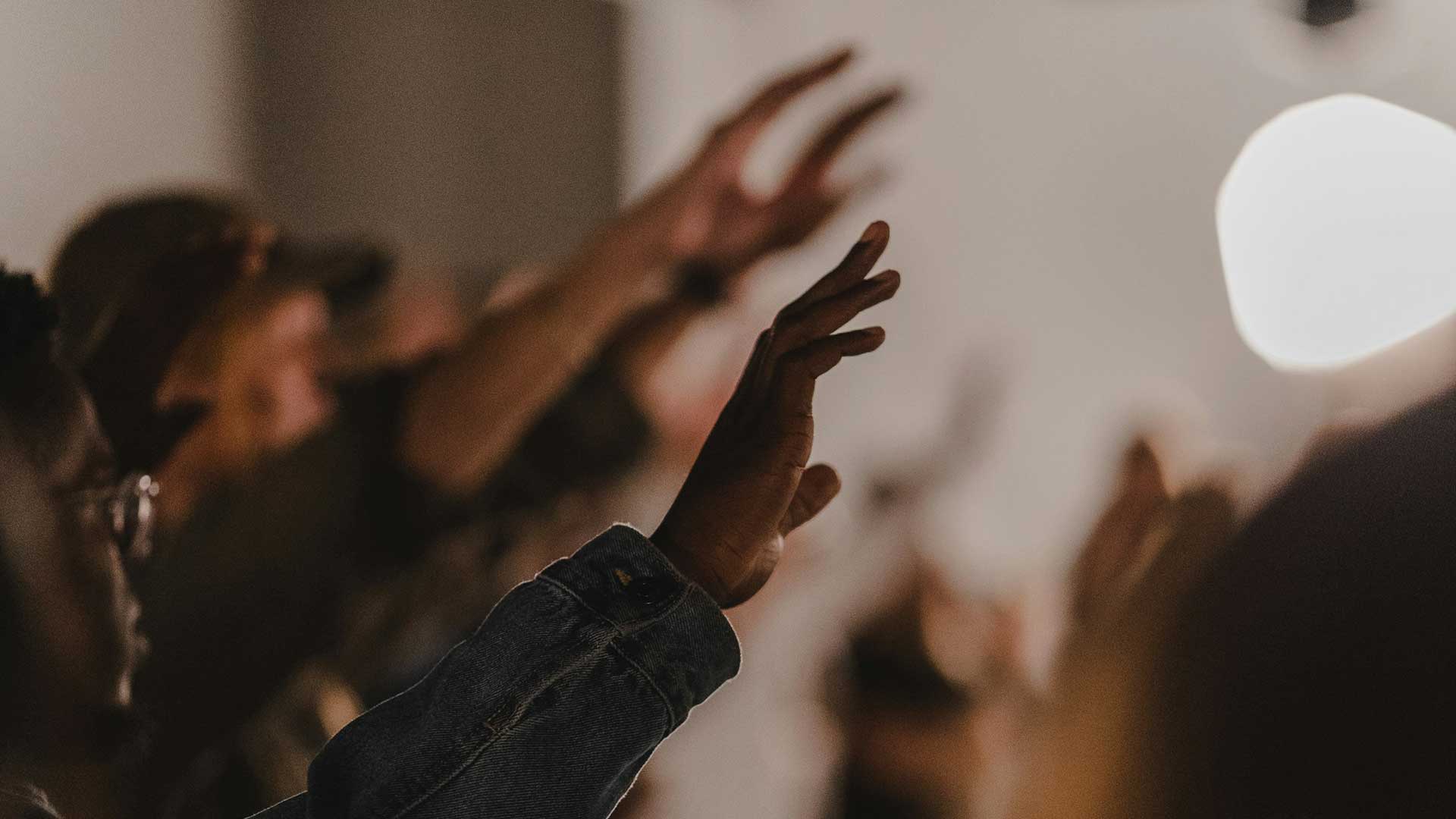 People raising hands in worship indoors