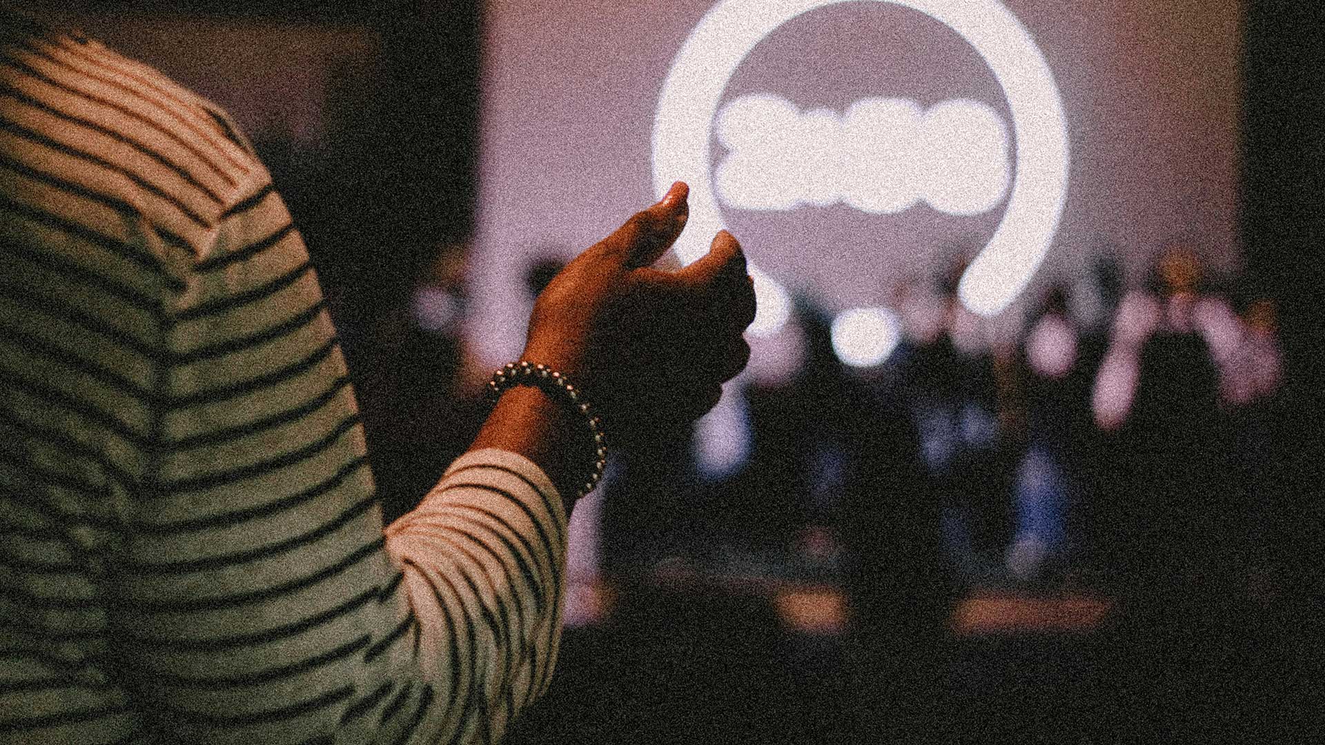 Person raising hand at indoor worship event