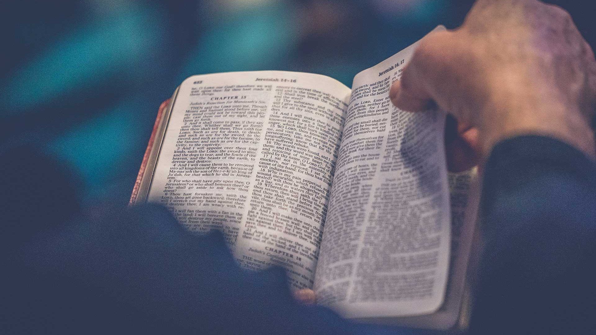 Person turning pages of an open Bible