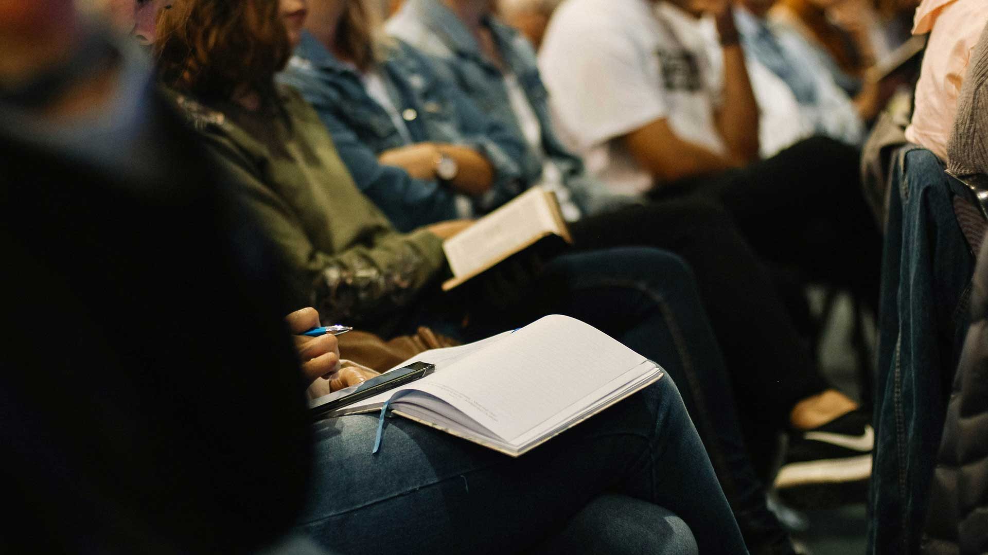 Audience members taking notes during a seminar